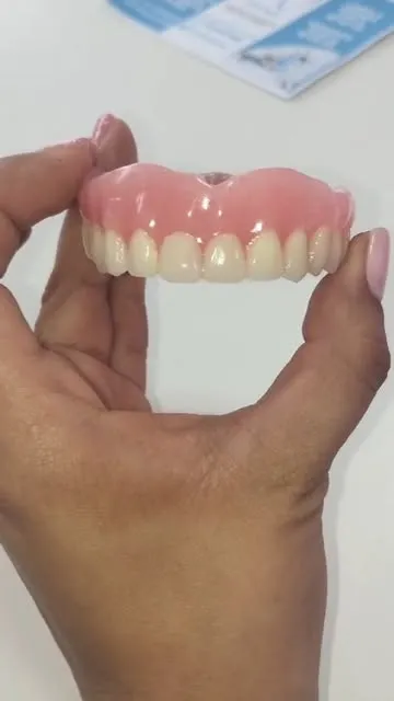 Prótesis dental superior sostenida con la mano